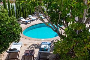 uma piscina com cadeiras, cadeiras e árvores em Can Fuentes em Cala Vadella