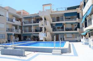 a large apartment building with a swimming pool in front of it at Naufragos Beach Apartment in Torrevieja