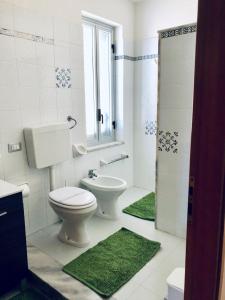 La salle de bains est pourvue de toilettes et d'un lavabo avec des tapis verts. dans l'établissement Attico Giusy, à Balestrate
