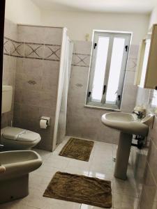 une salle de bain avec un lavabo et des toilettes et une fenêtre dans l'établissement Attico Giusy, à Balestrate 27 autres photos