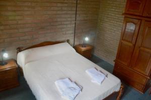 1 dormitorio con 1 cama con 2 toallas en LA TOMA Complejo de Montaña - Cabañas y Habitaciones en Hosteria en Mina Clavero