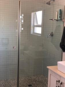 uma casa de banho com uma cabina de duche em vidro e um lavatório. em Views at 69 B&B em Langebaan
