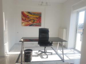 a desk with a chair in a room with a painting at NN Larisa Deluxe Apartment in Larisa