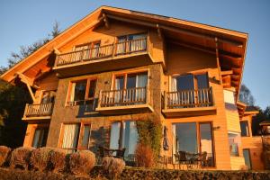 a large wooden house with balconies and tables at Hotel & Apart Hotel Monte Verde in Pucón