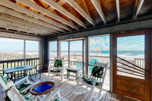 a room with chairs and tables on a deck with windows at Sho-rest in Folly Beach