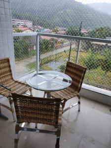 a glass table and two chairs on a balcony at Apto Praia das Toninhas in Ubatuba