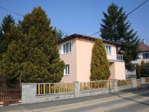 ein rosafarbenes Haus mit einem Zaun und Bäumen in der Unterkunft Apartmán Wolkrovka in Franzensbad