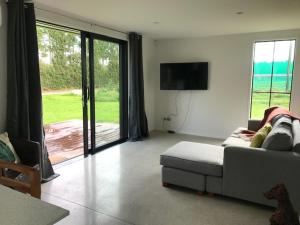 a living room with a couch and a flat screen tv at Lakin' it easy Cottage in Karapiro