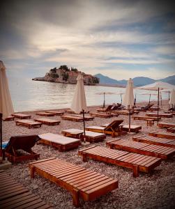 a group of lounge chairs and umbrellas on a beach at Sound of the Sea Apartment in Sveti Stefan