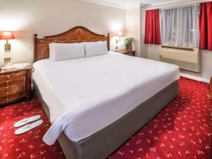 un grande letto bianco in una camera d'albergo con tappeto rosso di ibis London Earls Court a Londra