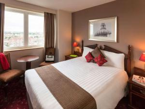 una camera d'albergo con un grande letto e una sedia di ibis London Earls Court a Londra