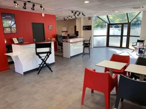 a restaurant with red walls and tables and chairs at Ibis Styles Paris Saint Denis La Plaine in Saint-Denis