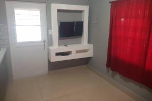 sala de estar con TV y cortina roja en Always Summer Inn, en Culebra