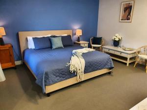 a bedroom with a large bed with blue walls at The Lancefield Lodge in Lancefield