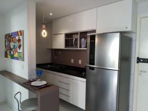 a kitchen with a stainless steel refrigerator and white cabinets at Flat Terreo Muro Alto Condomínio Clube com Sala Reversível para segundo quarto in Porto De Galinhas