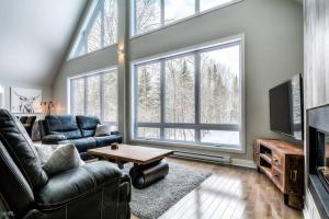 un soggiorno con divani e una grande finestra di 3BDRM Zen Tremblant Chalet - Ski/Hike/Swim a Lac-Superieur