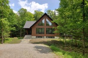 una casa nel bosco con un vialetto di ghiaia di 3BDRM Zen Tremblant Chalet - Ski/Hike/Swim a Lac-Superieur