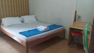 un letto con coperta blu e uno sgabello in una stanza di Seventeen homestay a Bandung