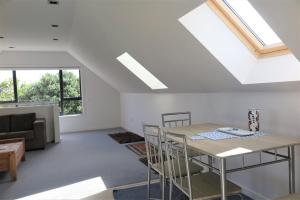 a kitchen and living room with a table and chairs at Ruru Lodge in Tawharanui