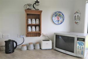 a kitchen with a microwave and a coffee pot at Ruru Lodge in Tawharanui