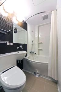 a bathroom with a white toilet and a tub and a sink at KOKO HOTEL Sapporo Ekimae in Sapporo