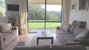 uma sala de estar com um sofá e uma mesa de centro em Kaka Lodge at Kotare House em Tawharanui