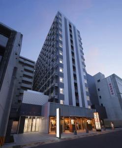 a tall building in a city with buildings at KOKO HOTEL Kagoshima Tenmonkan in Kagoshima