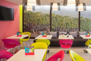 a dining room with colorful chairs and tables and a wall mural at ibis Styles Bordeaux Saint Médard in Saint-Médard-en-Jalles