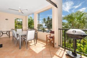 a balcony with a table and chairs and a grill at Mediterranean Beachfront Apartments in Yorkeys Knob
