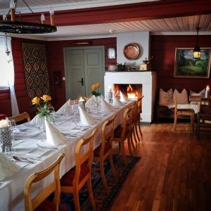uma sala de jantar com uma mesa longa com cadeiras e uma lareira em Sanner Hotell em Gran