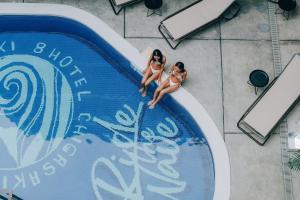 two women in bathing suits are sitting in a swimming pool at 8HOTEL Chigasaki in Chigasaki