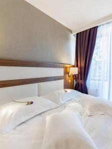 ein Bett mit zwei weißen Kissen und einem Fenster in der Unterkunft Hotel Miruna - New Belvedere in Poiana Brașov