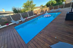 - une piscine avec une terrasse en bois et de l'eau bleue dans l'établissement Agréable Maison entre Bordeaux et le Bassin, à Saint-Jean-dʼIllac