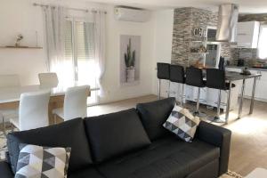 uma sala de estar com um sofá preto e uma cozinha em Agréable Maison entre Bordeaux et le Bassin em Saint-Jean-dʼIllac