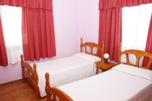 2 Betten in einem Zimmer mit roten Vorhängen in der Unterkunft Apartamentos Nelly in Valle Gran Rey