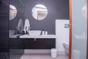 a bathroom with two sinks and two mirrors at Pelicans View in Yzerfontein