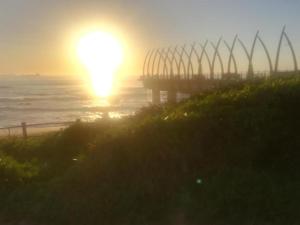 una puesta de sol sobre el océano con un muelle en Pearls of Umhlanga Apts, en Durban