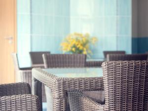 a table with wicker chairs and a vase of flowers at Kamanos in Utena