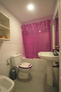 a bathroom with a pink shower curtain and a toilet and sink at Apartamento CasaTuris enfrente al mar en Playa Muchavista C102 in El Campello