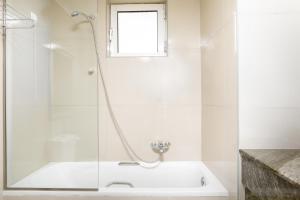 a white bathroom with a tub and a window at Sovereign Beach Hotel in Kardamaina