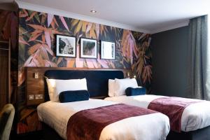 2 camas en una habitación de hotel con un mural en The Merlin by Innkeeper's Collection, en Alderley Edge