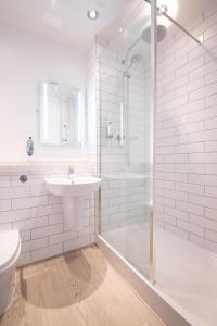 y baño blanco con lavabo y ducha. en The Merlin by Innkeeper's Collection en Alderley Edge