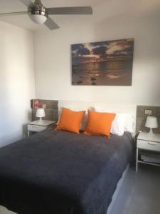 een slaapkamer met een bed met oranje kussens en een plafondventilator bij ALCALDE MARCIAL SANCHEZ VELAZQUEZ 15 in Caleta De Fuste