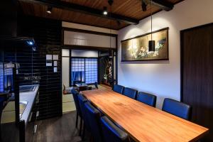 una sala da pranzo con un lungo tavolo in legno e sedie blu di Gojozaka Samurai Machiya a Kyoto