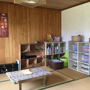 Zimmer mit einem Tisch und Regalen mit Büchern in der Unterkunft Shimaotoya in Iriomote