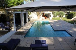 a swimming pool with an umbrella and chairs at Residence Vive la Vie in Franschhoek