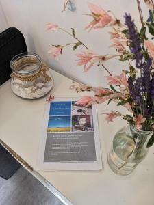 a table with a magazine and a vase of flowers at Gästehäuschen „kleine Auszeit“ in Greifswald