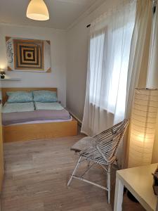 a bedroom with a bed and a chair and a window at Gästehäuschen „kleine Auszeit“ in Greifswald