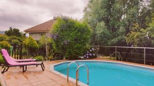 uma piscina num quintal com uma cadeira rosa ao lado em Casa Rural Area con piscina em Gondomar