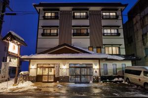 um edifício com neve no chão à sua frente em The Address Akakura em Myoko